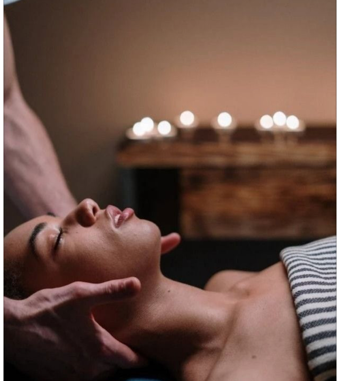 Clienta relajada recibiendo un masaje craneal y facial con velas